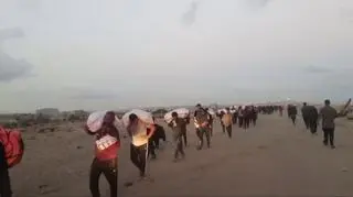 Palestyńczycy niosą torby z pomocą w Rafah w Strefie Gazy